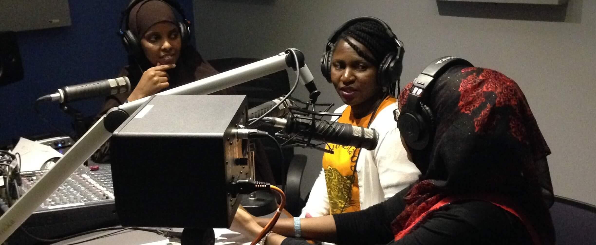 Somali Radio Ergo. Three Somali women sit behind microphones in a radio studio.